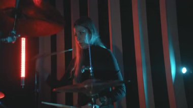 Genç bir kadın canlı müzik performansı ya da prova sırasında enerjik bir şekilde davul çalıyor.