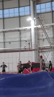 Genç erkek sırıkla atlamacı kapalı alanda atletizm eğitimi sırasında bardan başarıyla çıkıyor.