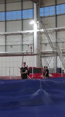 Kararlı erkek sırıkla atlamacı kapalı alanda atletizm eğitimi sırasında barı boşaltıyor.