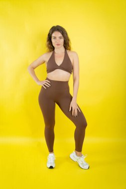 Kahverengi spor sutyen ve tayt giyen, spor ve aktif yaşam tarzını temsil eden bir kadın.