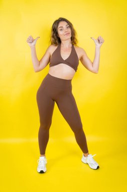 Atletik giyinen genç bir kadın kendine güvenini ve gururunu gösteriyor.