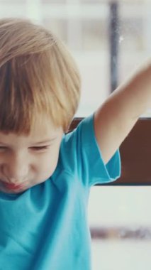 Pencerenin önünde duran küçük bir çocuk.