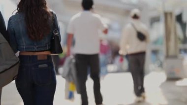 Tanımlanamayan insanlar kameradan uzaklaşıyorlar. Parlak, bulanık bir şehir caddesinde.