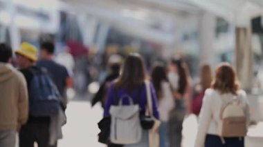 Meşgul bir kentsel alanda, yumuşak bir arka planı olan tanınmayan insanlar kameradan uzaklaşıyorlar.