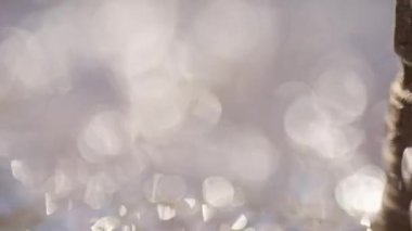 Odaklanmamış su yüzeyi güneşte parlıyor ve parlıyor. Parıldayan bir ışık yaratıyor.