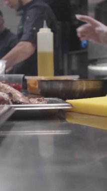 Kalabalık bir mutfak ortamında yemek pişirmek ve yemek hazırlamakla meşgul bir grup insanı bir barda veya restoranda izleyin..