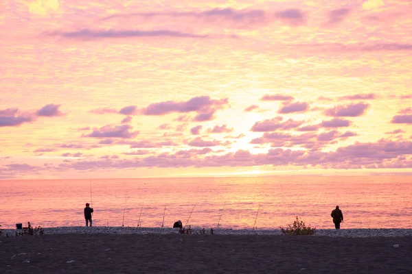 Fishermen on the sea sunset background.