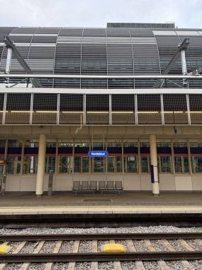 Viyana, Avusturya - 11 Ekim 2025: OeBB tren istasyonu Handelskai 'nin arka planında Rivergate ofis binasının metal levhaları bulunan boş platformu. Dikey.