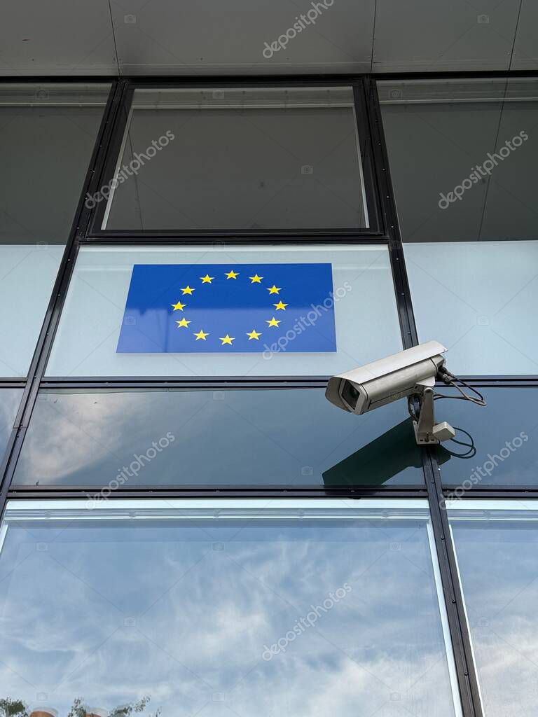 Vienna, Austria - October 20, 2025: CCTV camera and EU flag on glass facade of liaison office building of European Parliament 