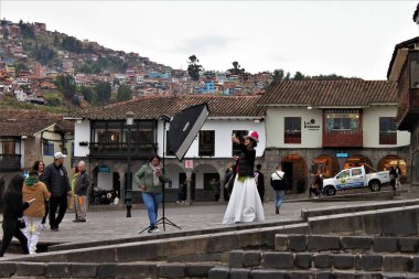 Cusco, Peru - 25 Mayıs 2025: Şehir merkezindeki Plaza de Armas 'da ışıklandırma şemsiyesi yardımıyla şık elbiseli ve akıllı telefon fotoğraflı bir bayanın olduğu sokak sahnesi. En yeni moda eğilimlerini sunuyorum..