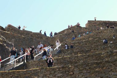 Ollantaytambo, Peru - 26 Mayıs 2025: Ollantaytambo arkeoloji sahasındaki Pumatallis tarım arazilerine giden dik yamaçlara tırmanan turist kalabalığı.
