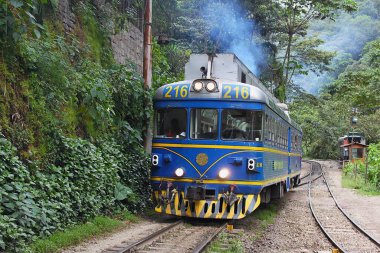 Aguas Calientes, Peru - 27 Mayıs 2025: Machupicchu Pueblo istasyonu yakınlarındaki tren yolu, Ollantaytambo 'dan gelen kendine özgü mavi Perurail treni ve dar Urubamba vadisi. Ferrocarril del Sur.