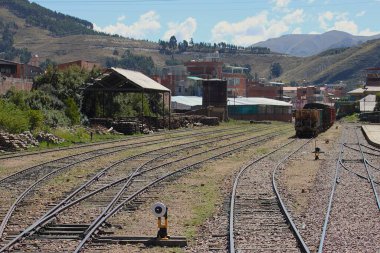 Cusco, Peru - 28 Mayıs 2025: Sicuani 'deki tren istasyonu ve tren yolu tersanesi, şalterli raylar, demiryolu yolcularının depolanması ve park halindeki yük vagonları. Kesilmiş boyalı yamaç harfleri..
