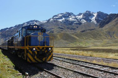Cusco, Peru - 28 Mayıs 2025: Peru Demiryolu tarafından işletilen Titicaca treniyle La Raya sıradağlarının etkileyici panoramik manzarası. Ferrocarril del Sur. Lokomotif ALCO MLW Serisi C-26 DL-560D, No. 653.