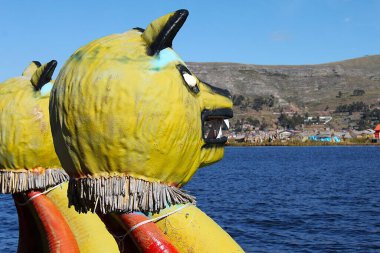 Puno, Peru - 29 Mayıs 2025: Uros Yüzen Adası 'ndaki tipik renkli kamış teknesinin pruvasında sarı boyanmış el yapımı, korkunç kamış heykelciğinin ayrıntıları. Titicaca Gölü 'ndeki Uros Adaları veya Uru Adaları.