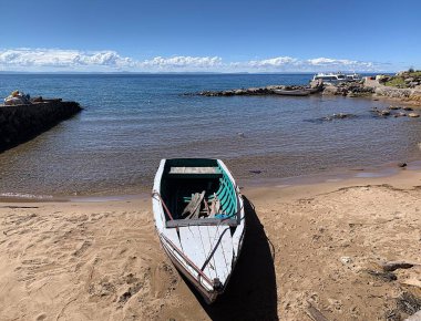 Isla Taquile, Puno, Peru: Puerto Huayllano yakınlarında Titicaca Gölü 'nde uzanan kayık. Bulutlar büyük bir yükseliş nedeniyle alçaktan sarkmış görünüyor. Derin mavi su ve bulutsuz gökyüzü.