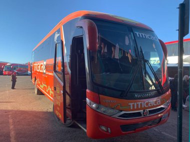 Puno, Peru - 30 Mayıs 2025: Orange Titicaca Xperience otobüsü Peru Cumhuriyeti 'ni Plurinational State of Bolivia' ya bağlıyor. Terminal Terrestre Puno 'daki otobüs durağından kalkış için bekliyor.