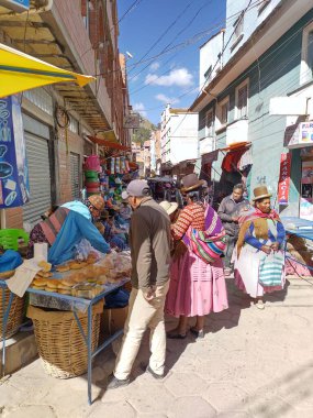 Copacabana, Bolivya - 31 Mayıs 2025: Geleneksel kostümlü yerel kadınlarla sokak pazarında renkli bir koşuşturma ve koşuşturma. Bölgesel ve mevsimlik meyve, sebze, baharat, taze pişmiş ekmek.. 