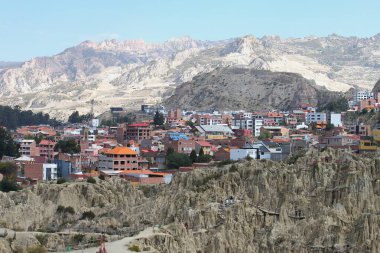 La Paz, Bolivya - Haziran 01, 2025: Valle de la Luna veya Ay Vadisi 'nin tuhaf kil ve kaya kulelerinin panoramik görüntüsü. Kaya yarıkları, kraterler ve piramitler. Yakınlardaki konut binaları.