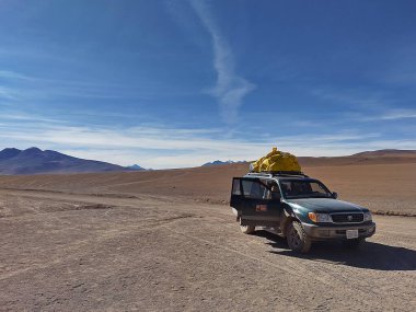 Sur Lipez, Potosi, Bolivya - 3 Haziran 2025: Atacama Çölü 'nün Siloli bölgesinde sonu gelmeyen kapıları açık bir Offroad aracı. Ufkun arkasındaki güçlü volkanların zirveleri. Avaroa And Hayvanat Bahçesi Ulusal Rezervi.