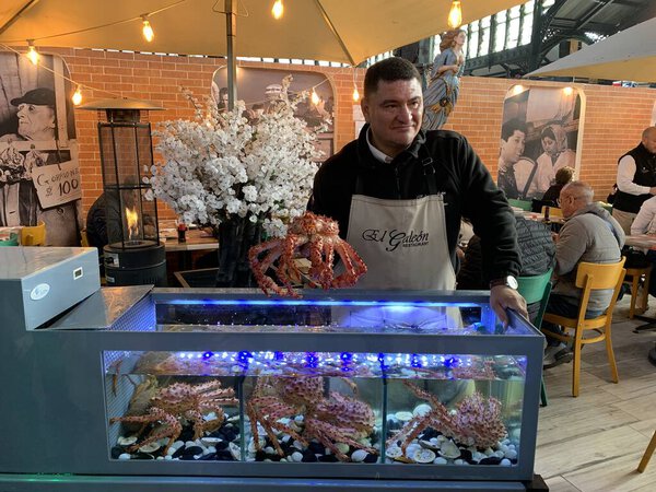 Сантьяго, Чили - 07 июня 2025 года: Ресторан официант представляя свежий улов утром в историческом Mercado Central Market Hall. Здоровые морепродукты из вод Тихого океана.