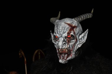 Gaenserndorf, Aşağı Avusturya - 28 Kasım 2025 Krampus 'un korkunç yüzüne yakın çekim. Korkunç kostüm. Perchtenlauf, Alp folklorik geleneği. Parlayan kırmızı gözleri olan boynuzlu antropomorfik figür..