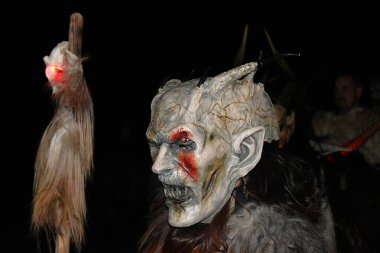 Gaenserndorf, Aşağı Avusturya - 28 Kasım 2025: Krampuslauf sırasında boynuzlu, kürklü, dişli ve asık suratlı korkunç şeytani kostümlerle gösteri yapan bir grup adam. Boynuzlu antropomorfik figürler.