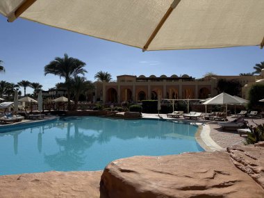 Marsa Alam, Mısır - 11 Aralık 2025: Steigenberger Coraya Sahili üzerindeki yüksek kayalık yerden mavi gökyüzü altındaki doğu mimarisine bakın. Lüks otelde güneşli bir gün..