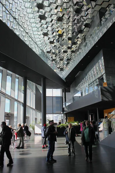 Reykjavik, İzlanda - 28 Ağustos 2015: Ziyaretçiler, Harpa konser salonu ve konferans salonunun iç kesimlerinde ülkenin bazalt manzarasından esinlenilmiş belirgin renkli cam cepheleriyle harikalar yaratıyorlar. Dikey.
