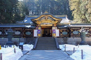 Nikko, Tochigi, Kanto, Japonya - 18 Şubat 2016: Rinno-ji Tapınağı kompleksindeki Taiyuin mozolesinin altın Karamon kapısı kar ve kış günü arka planda uzun sedir ağaçları.