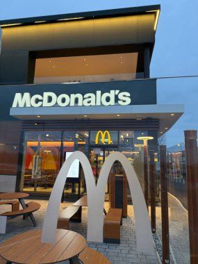 Gaenserndorf, Aşağı Avusturya - 08 Şubat 2026: McDonald 's ve McCafe binasının gece parlayan tabelalı dış görünüşü. Küresel fast food zincirinin çağdaş perakende mimarisi.