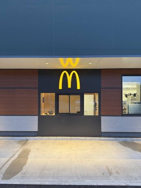 Gaenserndorf, Aşağı Avusturya - 08 Şubat 2026: McDonald 's McDrive ve McCafe' nin gece görüşü aydınlatma işaretleriyle. Fast food servis şeridi ve restoran mimarisi. Dikey.