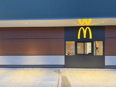 Gaenserndorf, Aşağı Avusturya - 08 Şubat 2026: McDonald 's McDrive ve McCafe' nin gece görüşü aydınlatma işaretleriyle. Fast food restoranı restoranı mimarisi. Boşluğu kopyala.