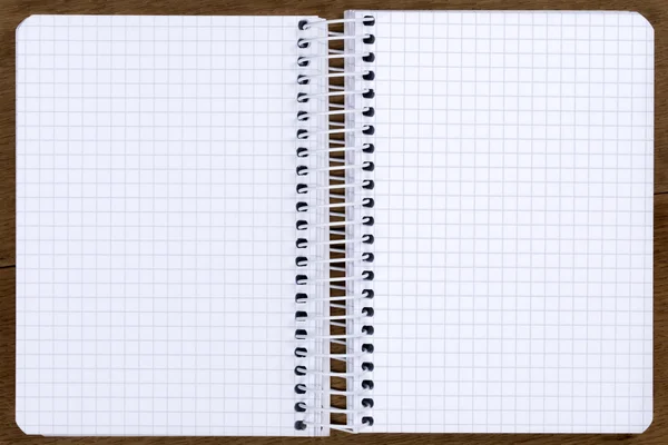 Otwarte puste spirala związane notebook z kwadratów papieru na dębowy stół — Zdjęcie stockowe
