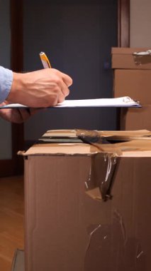 Dikey video kişi bir pano üzerinde bir belge imzalıyor, çoklu karton paketler ve paketlerin resepsiyonunu, ev teslimatını ve ticari lojistiği temsil ediyor