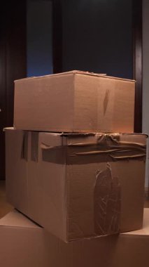 Dikey videocu çeşitli karton kutuları istifliyor, taşınma için kişisel eşyaları düzenliyor, paketleme, dağıtım ve depolama kavramlarını gösteriyor