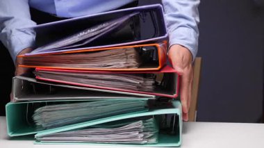 Ofis işleri, iş yükü ve idari işleri temsil eden, evrak ve dosyalarla dolu, taşmış bir yığın klasörü düzenleyen ve istifleyen kişiler