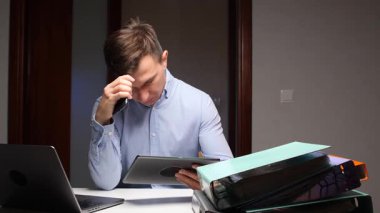 Şaşkına dönmüş işadamı birden fazla işten dolayı stresli ve yorgun hissediyor, bilgisayardaki, tabletteki ve loş bir ofis kabinindeki zahmetli iş yükü ile uğraşıyor.