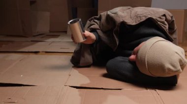 Dilenci yardım ister, sadaka verme sahnesi loş ışıkta, bireysel bağış isteyen, mukavva üzerinde uzanan kişi uzanmış elleriyle sessizce bozuk para toplar.