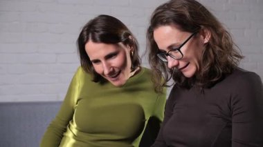 İki profesyonel kadın birlikte çalışıyor, yoğun bir şekilde bir dizüstü bilgisayara odaklanıyor, üretken bir tartışmaya girişiyor ve ortak bir iş projesi veya uzaktan çalışma verilerini analiz ediyorlar.