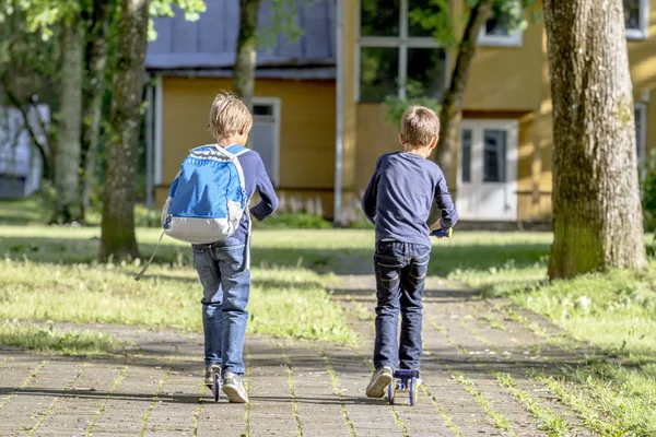 Niños montando con scooters al aire libre. Actividad de ocio. Vista desde atrás — Foto de Stock