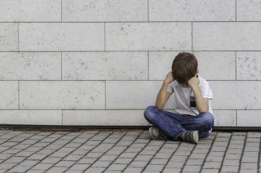 Üzgün, yalnız, mutsuz, hayal kırıklığına uğramış çocuk yerde tek başına oturuyor. Başını tutan çocuk, aşağı bak. Açık