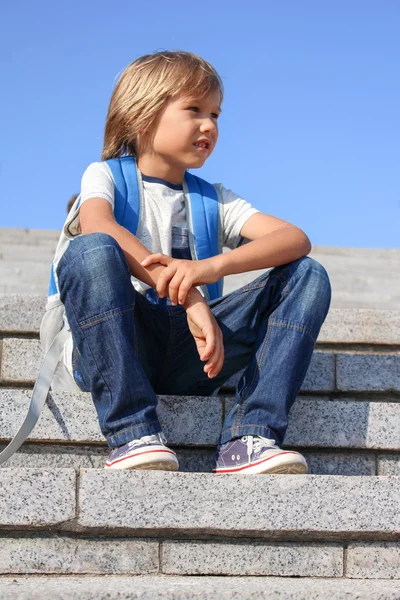 배낭을 들고 계단에 앉아 있는 귀여운 소년. 학교 개념으로 돌아가기. — 스톡 사진