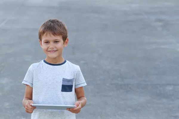 Sonriente chico con tableta PC. Fondo gris. Infancia, ocio, educación, aprendizaje, concepto tecnológico — Foto de Stock