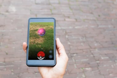 Vilnius, Litvanya - 24 Temmuz 2016: cep telefonu tutarak ve Pokemon Go - IOS Android cihazlar için Niantic tarafından geliştirilen bir artar gerçeklik yer-esaslı oyun oynayan kişi.