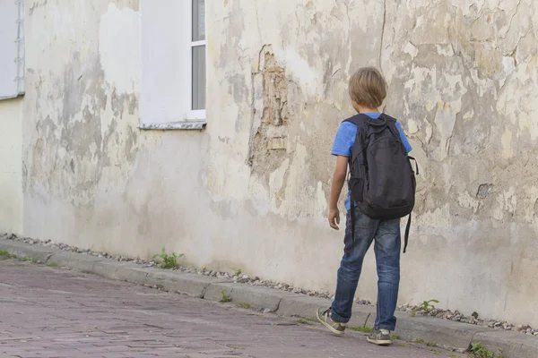 Un chico caminando por la calle con su mochila. Vista trasera. Educación de personas, escuela, viajes, concepto de ocio — Foto de Stock