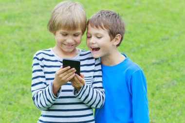 Çocuklar ile hareket eden telefon. Gülümseyen, ekrana bakarak, oyun veya uygulama kullanarak çocuk. Açık. Teknoloji eğitim eğlence insanlar kavramı
