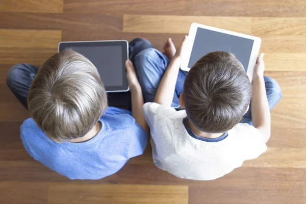 Los niños que usan tabletas PC sentado en el suelo de madera en casa. Vista superior. Educación, aprendizaje, tecnología, amigos, concepto escolar — Foto de Stock