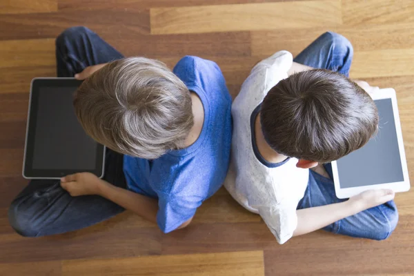 Children with tablets PC sitting on wooden floor at home. Top view. Education, learning, technology, friends, school concept — Stock Photo, Image