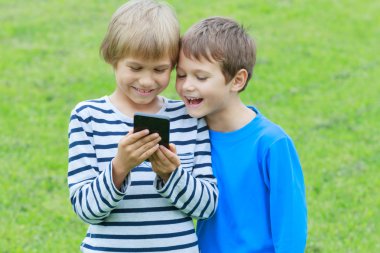 Çocuklar ile smartphone. Gülümseyen, ekrana bakarak, oyun veya uygulama kullanarak çocuk. Açık. Teknoloji eğitim eğlence insanlar kavramı